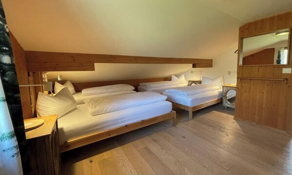 A room with two wooden beds, a wooden ceiling, and a small table with a lamp.