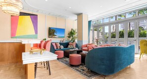 Eine moderne Lounge mit einem Tisch aus weißem Marmor, farbenfrohen Sofas und einem großen Fenster mit Blick ins Freie.