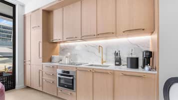 Une cuisine moderne avec des meubles en bois, un four Bosch, un évier avec un robinet doré et une machine à café.