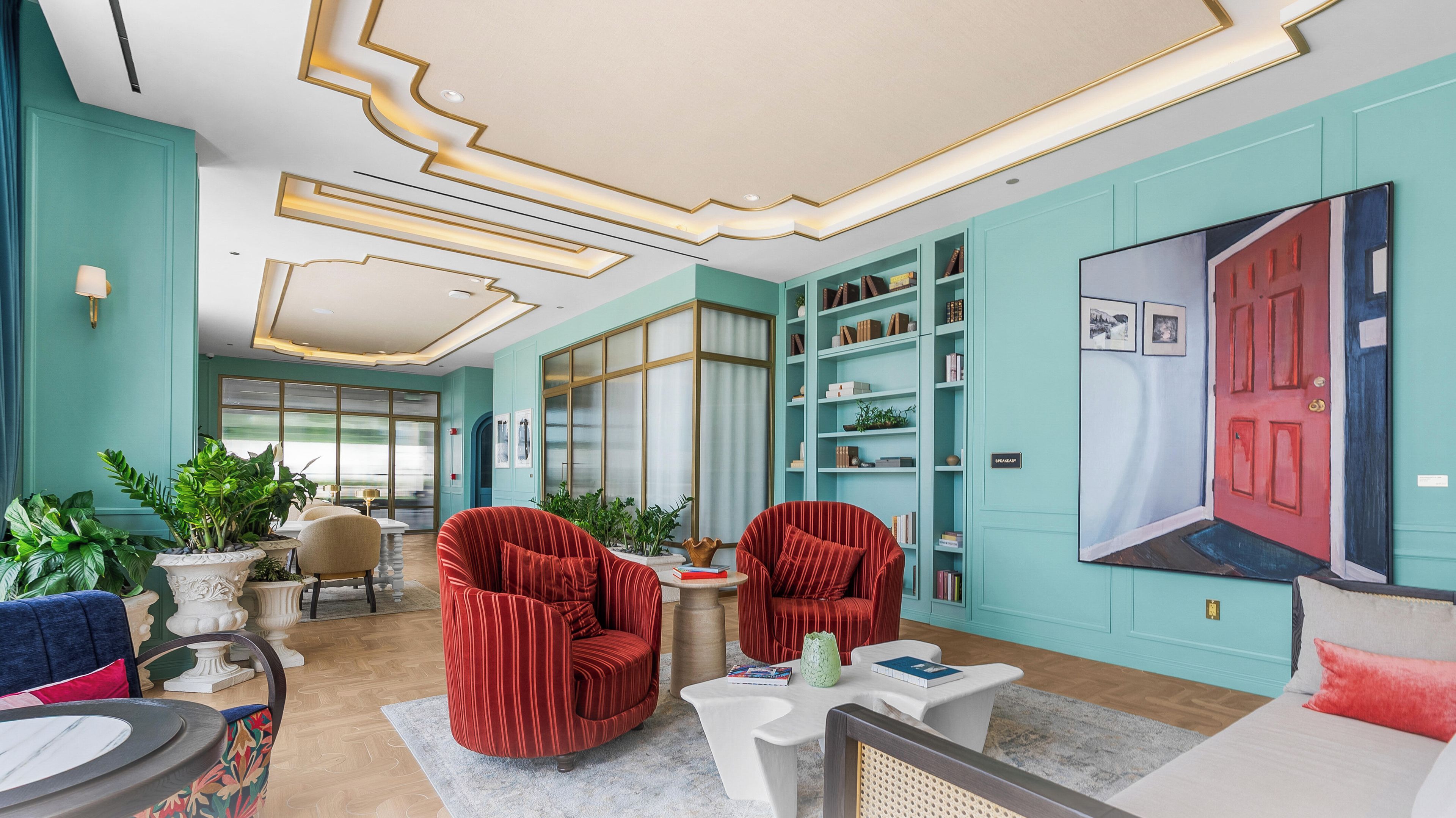 Amplia sala de estar con diseño moderno, que incluye sillones tapizados en rojo, una mesa de centro blanca y una estantería.