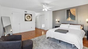Ein Schlafzimmer mit einem großen Bett, einem Deckenventilator und Kunstwerken an den Wänden.