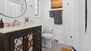 Ein Badezimmer mit Waschbecken, dunklem Schrank, Toilette und Duschvorhang.