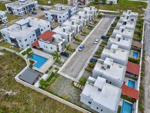 A residential area with multiple two-story buildings, a central road, and a swimming pool. - A Hidden Refuge Where Peace Meets Serenity (Punta Cana)