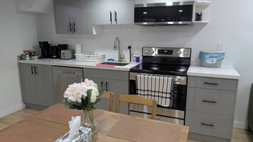 Una cocina moderna con armarios grises, electrodomésticos de acero inoxidable y una mesa de comedor de madera con un florero.