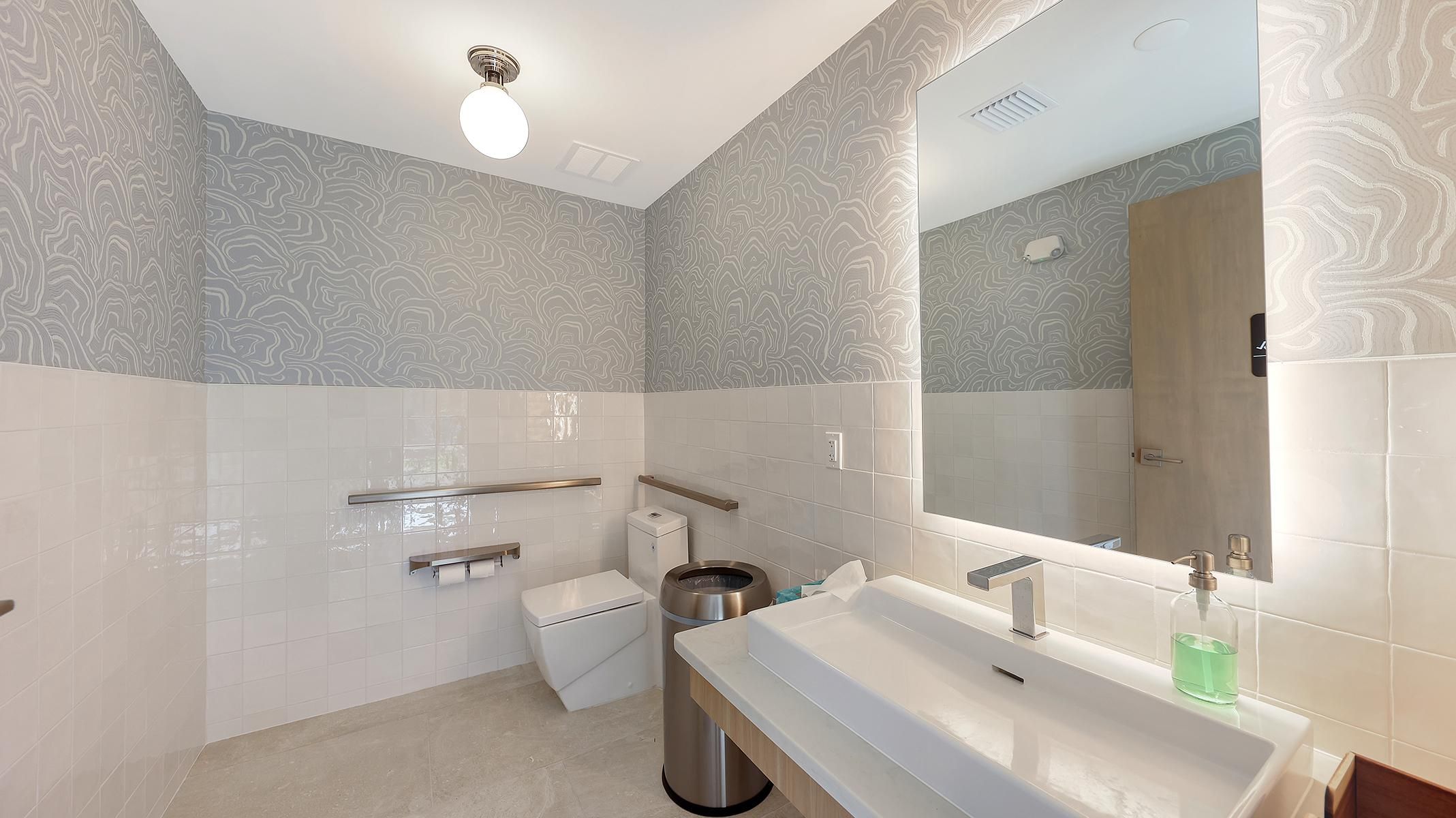 Een moderne badkamer met een grote spiegel, toilet, wastafel en douchetoilet.