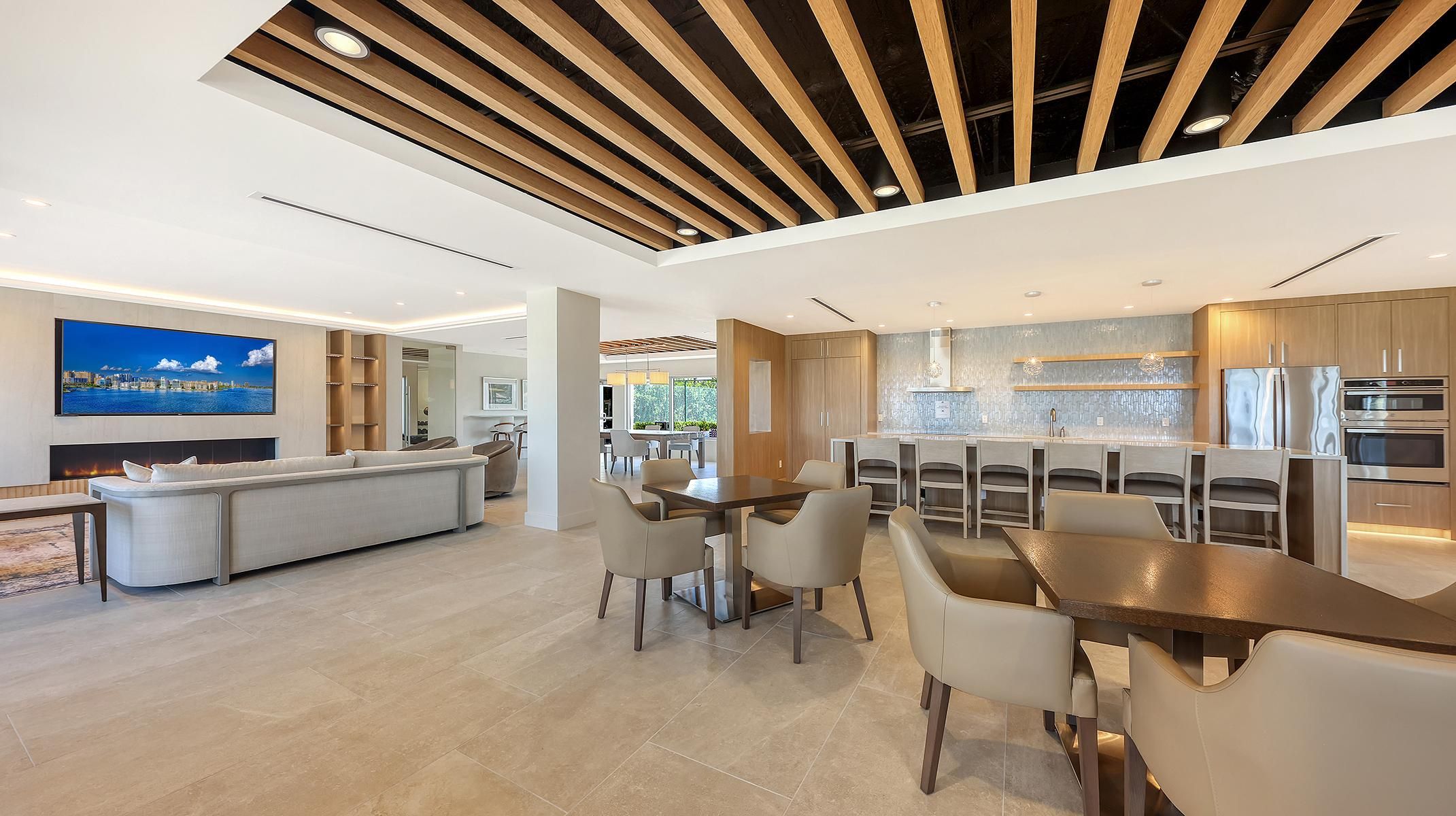 A modern kitchen with stainless steel appliances, a dining area with a wooden table and chairs, and a living area with a sofa and a flat-screen TV.