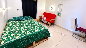 Ett sovrum med en säng, en röd soffa, en stol, en luftkonditioneringsanläggning och en spegel på väggen.