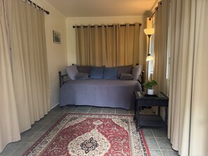 A bedroom with a bed, curtains, a lamp, a rug, and a small table with a plant. - Downtown Aiken Enjoyable 3-bedroom house-walking distance to downtown (Aiken)
