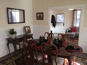 A dining area with a wooden table and chairs, a mirror, framed pictures, and a potted plant. - Downtown Aiken Enjoyable 3-bedroom house-walking distance to downtown (Aiken)