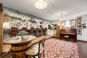 Ein Essbereich mit Holztisch und Stühlen, einem Klavier und einem roten Teppich mit Muster.