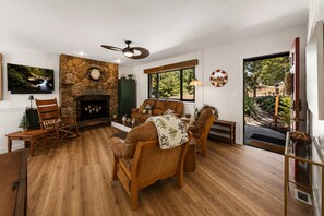 A cozy living room with a stone fireplace, wooden flooring, and comfortable seating. - Pine Nest Retreat Scenic Views and Private Saloon (Prescott)