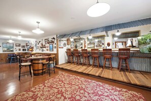 A spacious bar area with wooden chairs and a bar counter, surrounded by various framed pictures and a large mirror. - Pine Nest Retreat Scenic Views and Private Saloon (Prescott)