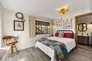 Ein Schlafzimmer mit einem Bett, einem Sessel, einem Fenster und einem Spiegel.