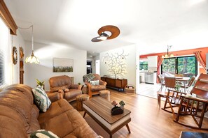 Ein geräumiges Wohnzimmer mit Ledersofas, einem Holztisch und einem Essbereich mit Holzstühlen.