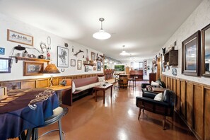 A spacious room with a wooden floor, a dining area with a table and chairs, a sofa, and a fireplace. - Pine Nest Retreat Scenic Views and Private Saloon (Prescott)