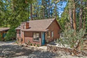 Une cabane en bois avec une cheminée, une porte d’entrée et un petit porche.