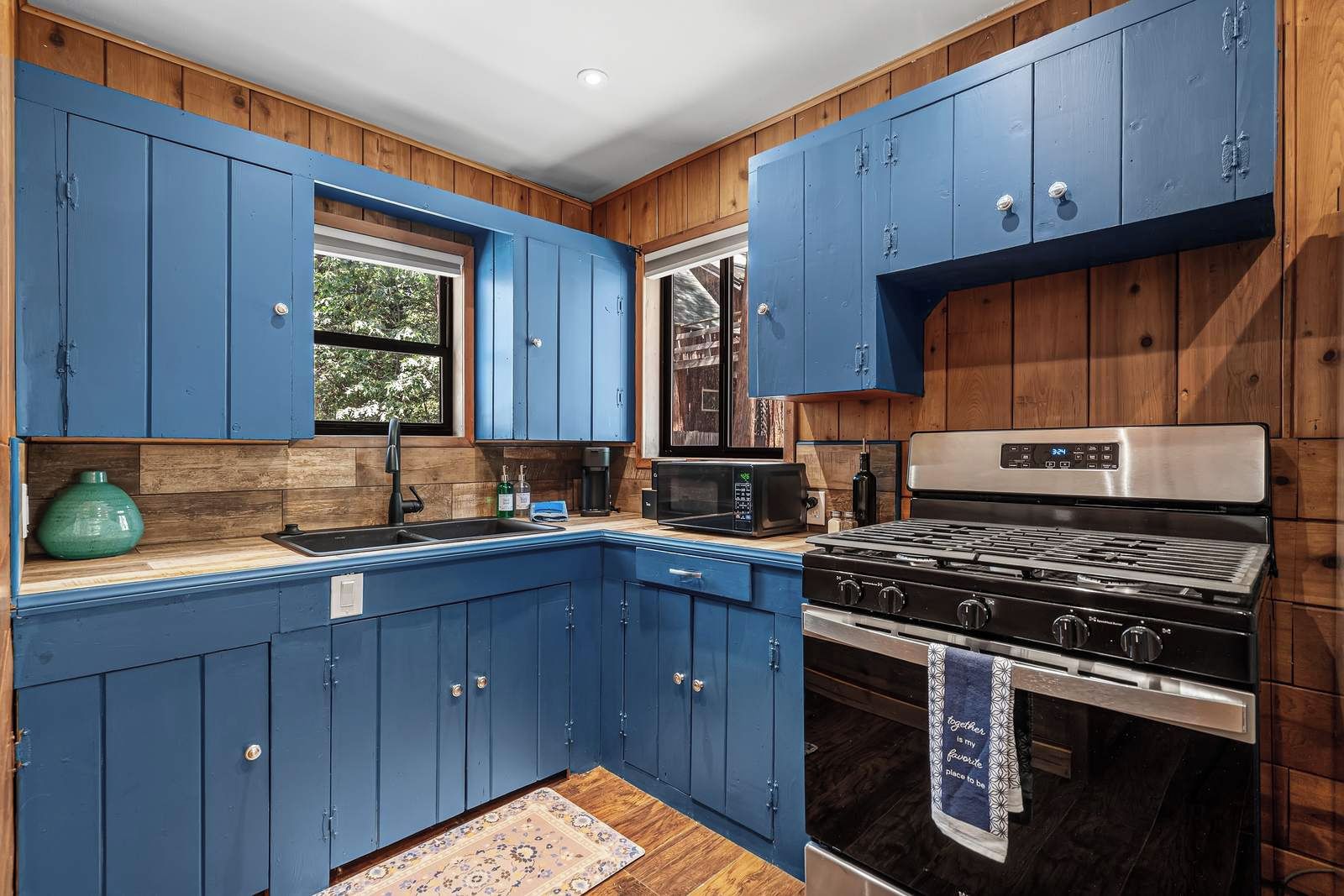 A kitchen with blue cabinets, a stainless steel stove, and a microwave.