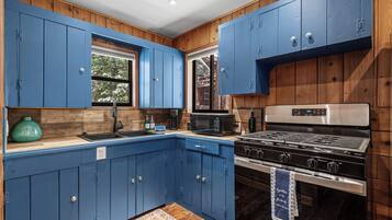 A kitchen with blue cabinets, a stainless steel stove, and a microwave.
