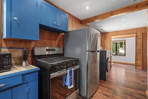 Une cuisine équipée d’une cuisinière à gaz, d’un réfrigérateur en acier inoxydable et de meubles de couleur bleue.