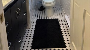 A bathroom with a toilet, a sink, and a black rug on the floor. - 3 Bedroom Argyle Mermaid by the sea (Neptune Township)