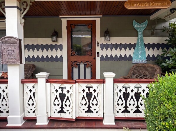A wooden porch with a decorative door, a sign reading 'The Argyle Mermaid,' and a mermaid tail sign.