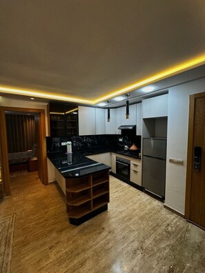 A modern kitchen with a central island, built-in appliances, and a wooden floor. - NEW Modern Apartment Heart of Mohammedia (Mohammedia)