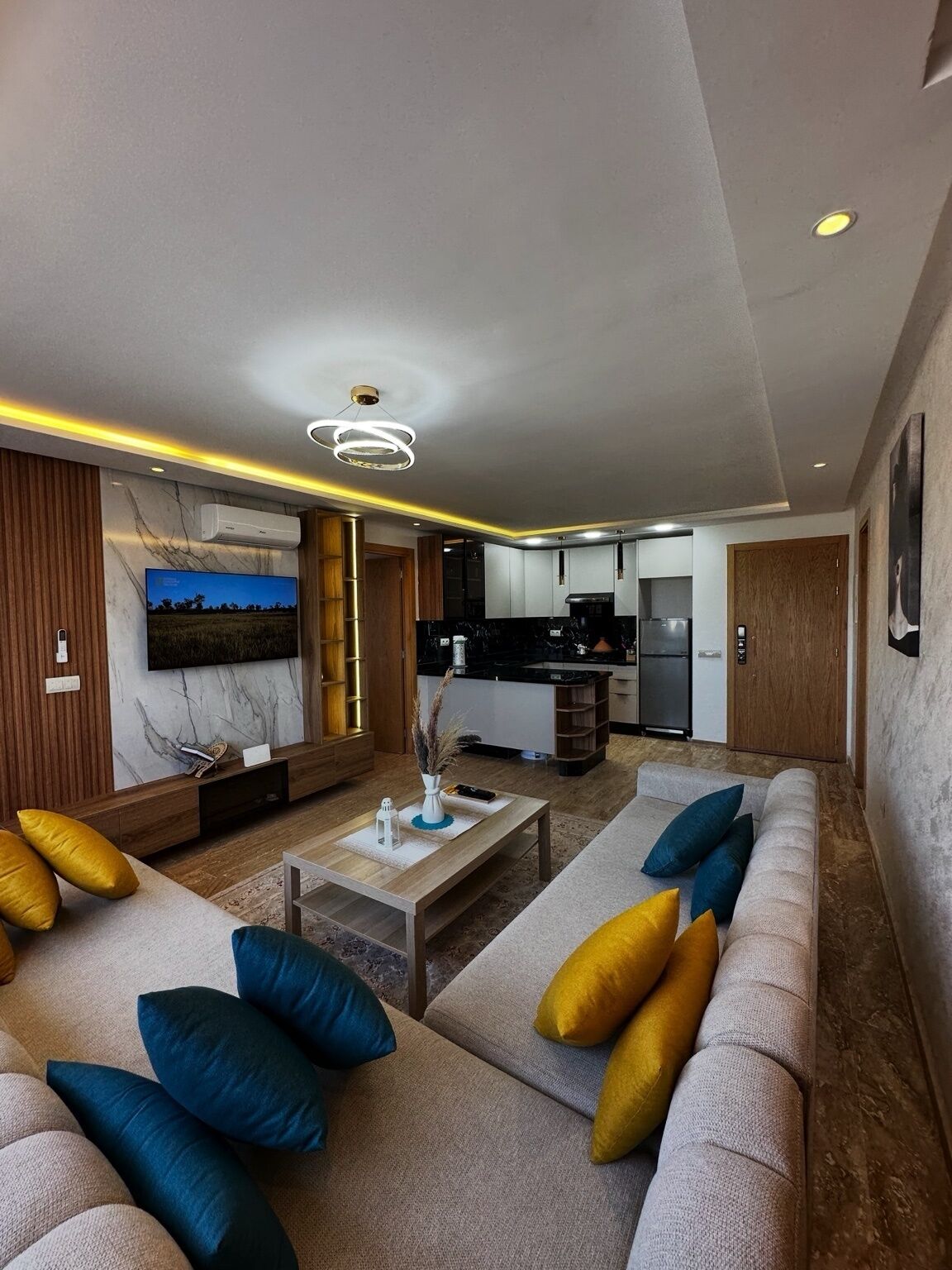 A modern living room with a sofa, coffee table, and a television mounted on the wall.