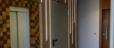 A modern hallway with a wooden wall, a checkered pattern door, and a marble floor.