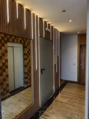 A modern hallway with a wooden wall, a checkered pattern door, and a marble floor. - NEW Modern Apartment Heart of Mohammedia (Mohammedia)