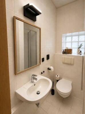 Un bagno moderno con lavandino, WC e un grande specchio.
