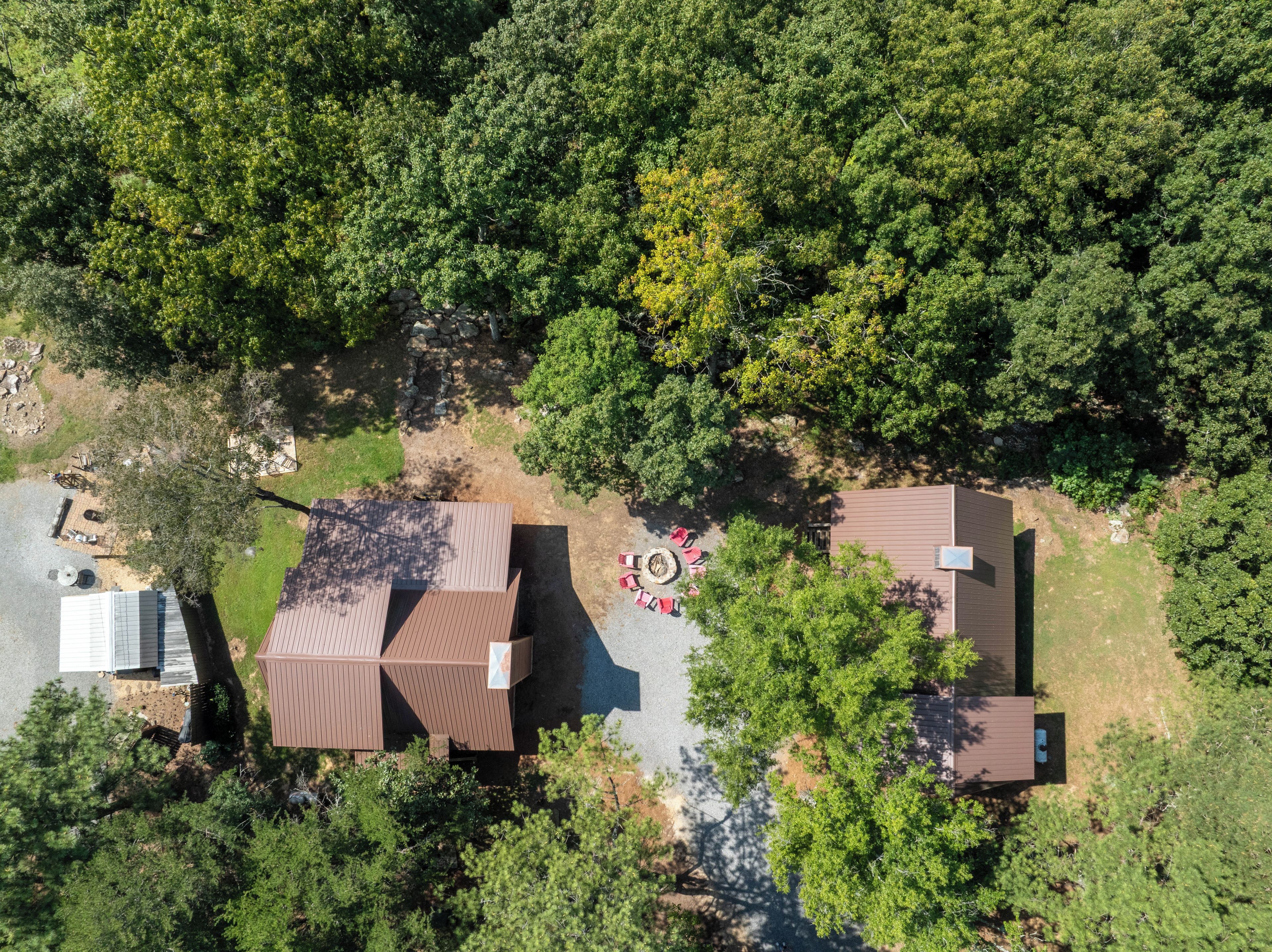 Vista aerea di una zona residenziale con diverse case, un vialetto asfaltato e un piccolo spazio esterno con posti a sedere.