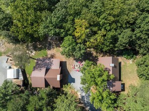 An aerial view of a residential area with multiple houses, a paved driveway, and a small outdoor seating area. - Fancy's Find homey cabin with breathtaking vistas! (Mentone)