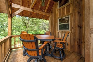Une terrasse en bois avec une table et des chaises, donnant sur une zone boisée.