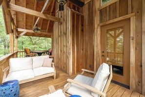 A wooden deck with a sofa and chairs, a ceiling fan, and a door with a window. - Fancy's Find homey cabin with breathtaking vistas! (Mentone)