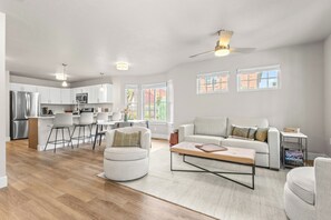 Un salon moderne avec un canapé, un pouf et une table basse.