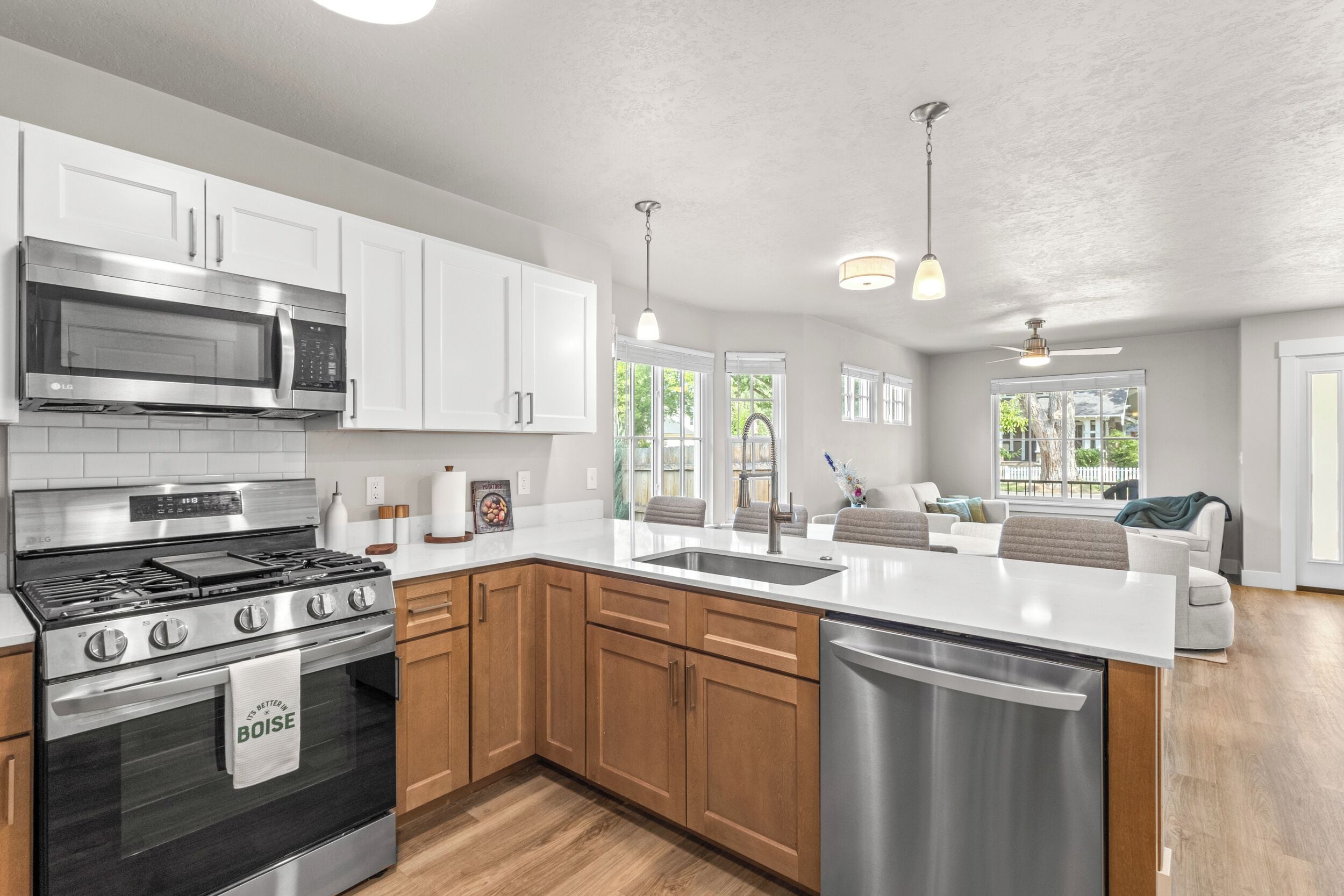 A modern kitchen with white cabinetry, stainless steel appliances, and a wooden floor.