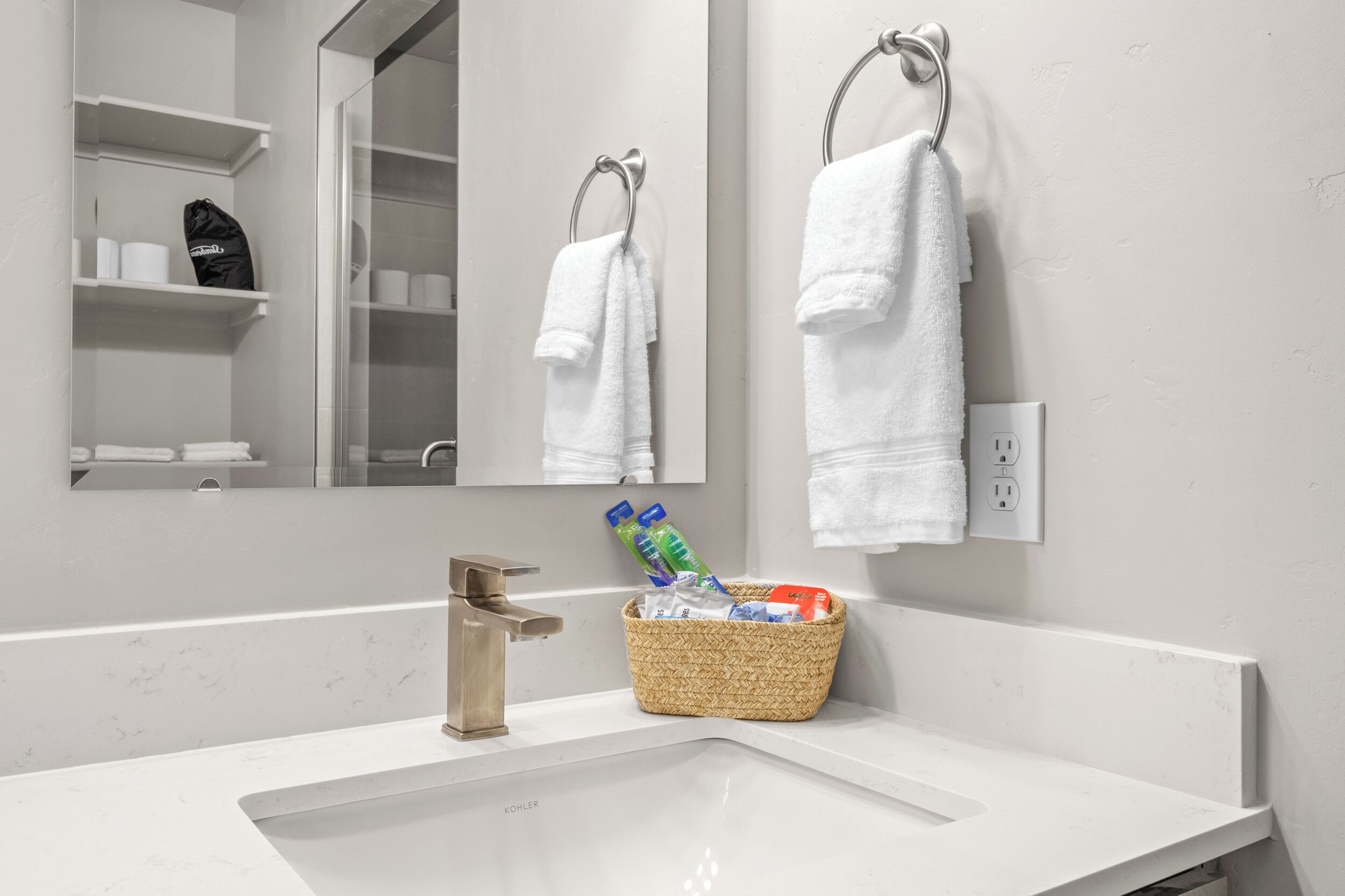 A bathroom with a white sink, a mirror, and two white towels hanging on hooks.