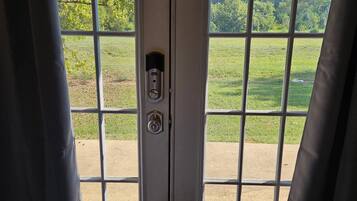 A door with a keypad lock and a view of a grassy field through the window.