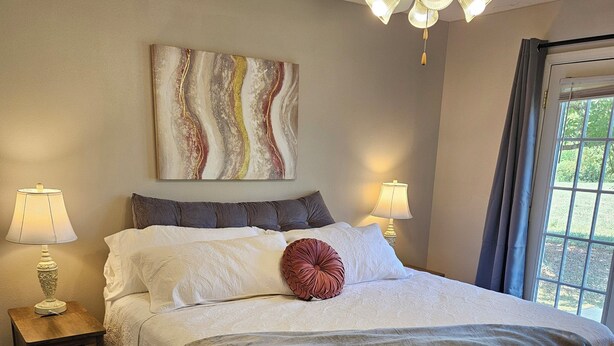 A bedroom with a bed, two bedside lamps, a ceiling fan, and a window with curtains. - Gameday Guesthouse 2BR/2BA updated townhome in fabulous Starkville 5 min to MSU (Starkville)