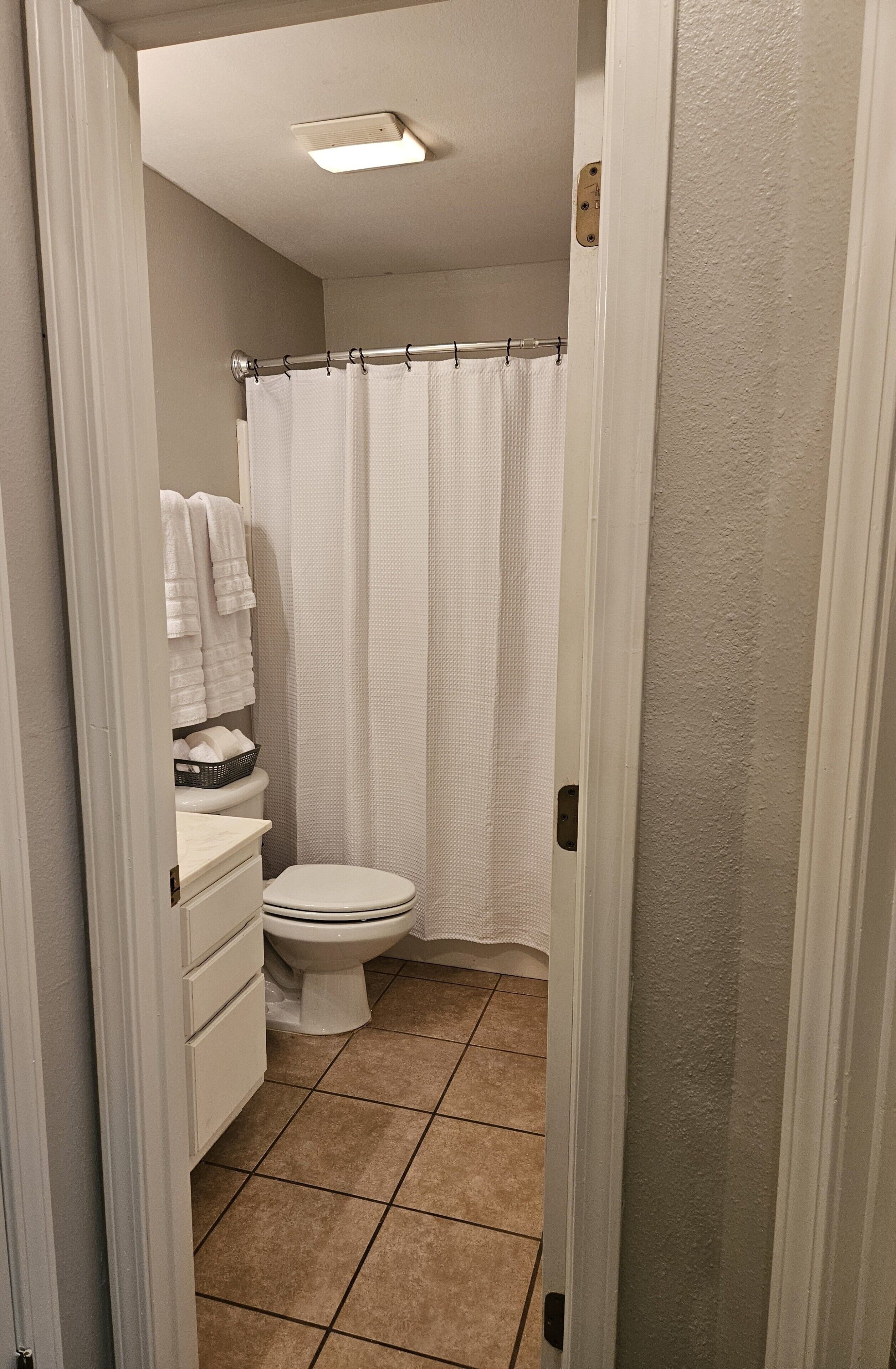 A bathroom with a toilet, a shower curtain, and a towel rack.