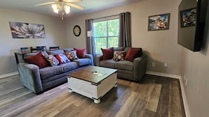 A living room with two sofas, a coffee table, a ceiling fan, and artwork on the walls. - Gameday Guesthouse 2BR/2BA updated townhome in fabulous Starkville 5 min to MSU (Starkville)