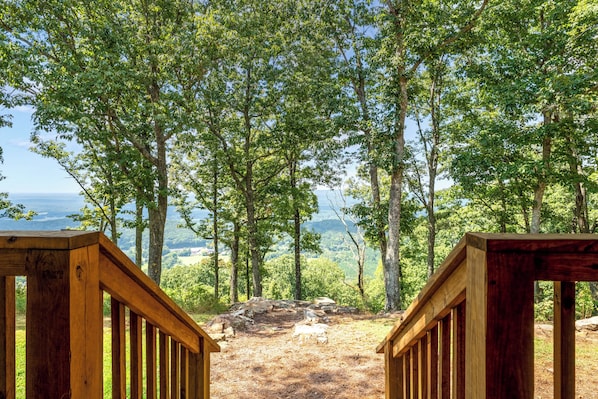 Eine Holzterrasse mit Blick auf bewaldetes Gebiet und eine ferne Landschaft.
