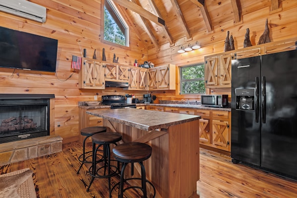 A wooden cabin interior with a kitchen, bar area, and a fireplace. - Pappy's Peace cozy cabin atop the Alabama Alps! (Mentone)