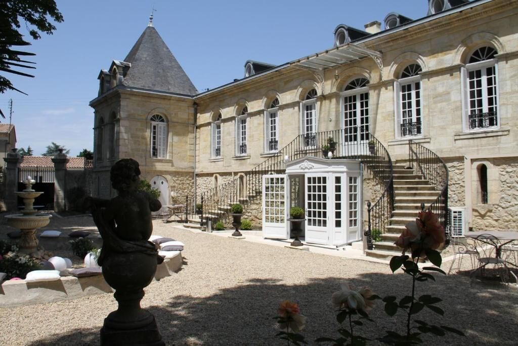 A courtyard with a fountain, a statue, and a building with a staircase and a door.