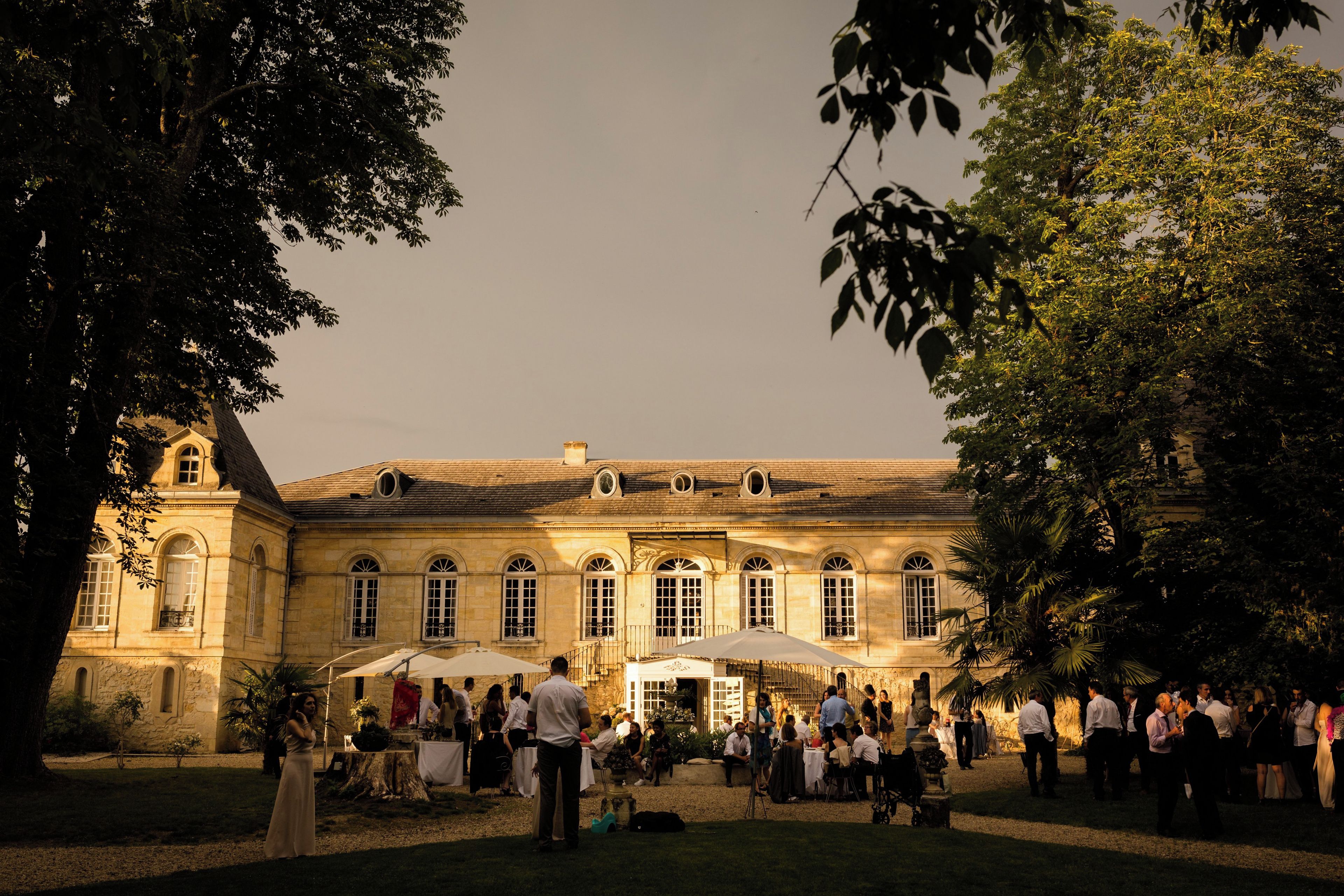 A historic building with a courtyard, outdoor seating, and a gathering of people.