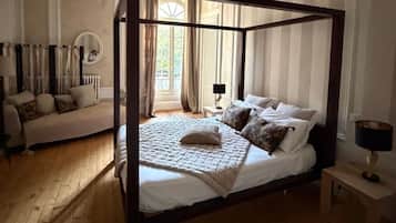 Un lit à baldaquin avec une courtepointe, une table de chevet avec une lampe et un canapé avec des coussins.