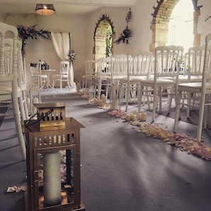 An indoor venue with white chairs arranged in rows, a carpeted floor, and a decorative lantern in the foreground.