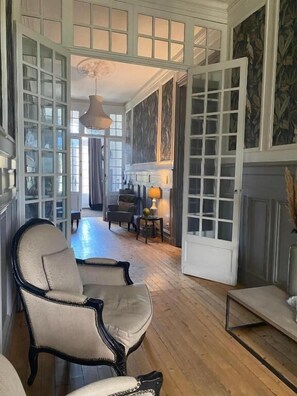 Una habitación amplia con piso de madera, un gran arco abierto y una chimenea.