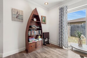 Ein Zimmer mit einer Holzbibliothek, einer Uhr und einem gerahmten Bild an der Wand.
