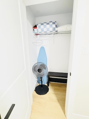 Ein kleines Zimmer mit Etagenbett, Standventilator und einer kleinen Bank.